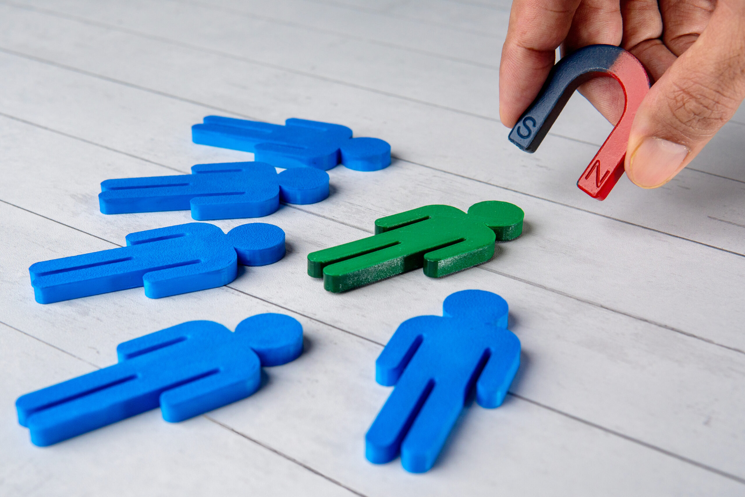 A magnet attracting a green figure from a group figures, representing lead generation.